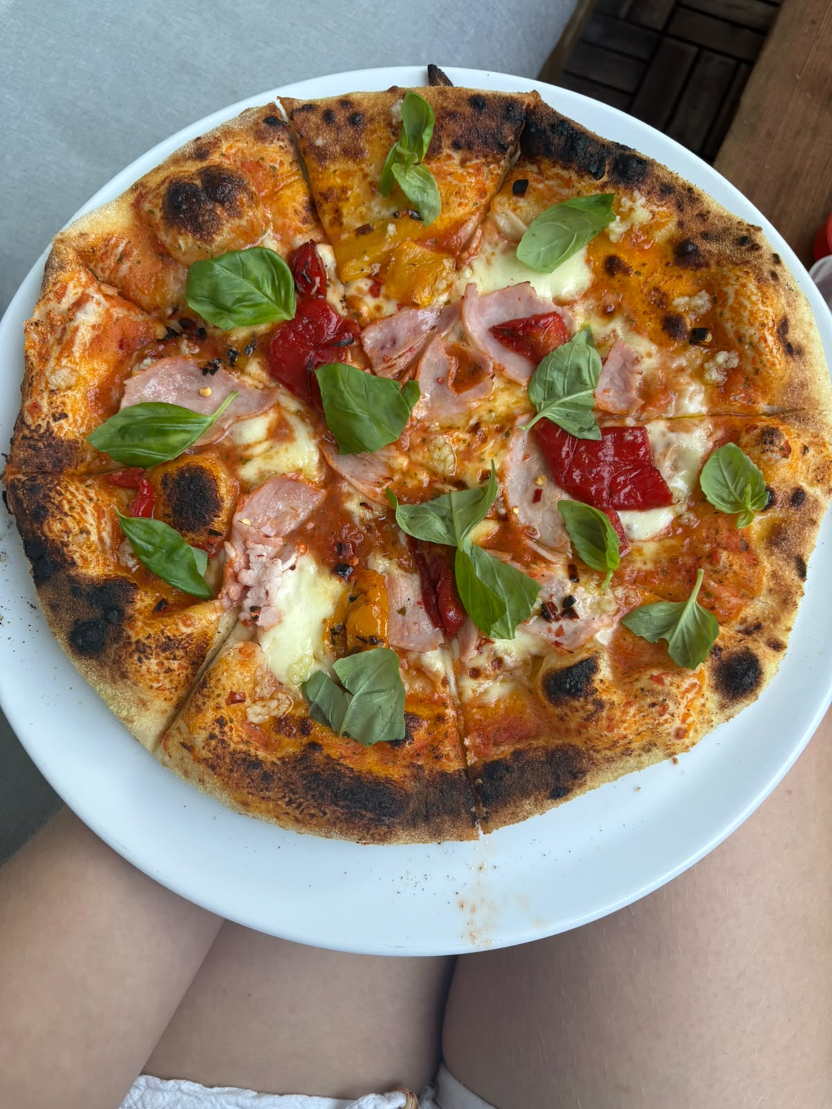 Freshly baked Neapolitan pizza with an airy rim, peppers, ham and basil